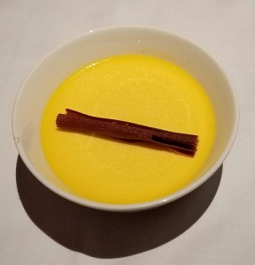 A photo of a passion fruit creme brulee with a cinnamon stick